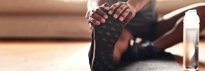 A person stretching their leg on a yoga mat.