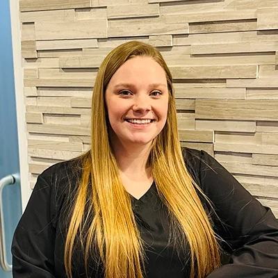 Support Coordinator Serenity Smiling In Front Of Tile Wall