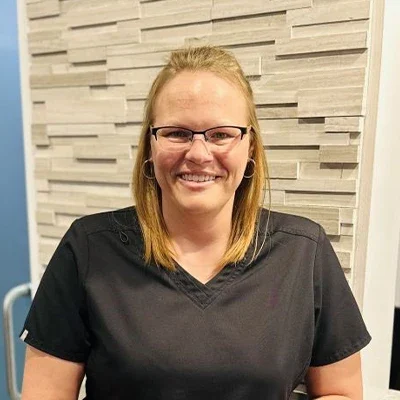 Chiropractic West St. Louis MO Amy Meet The Team Amy smiling in front of a brick wall.