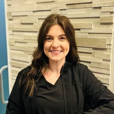 Chiropractic West St. Louis MO Elle Meet The Team Elle smiling in front of a brick wall.
