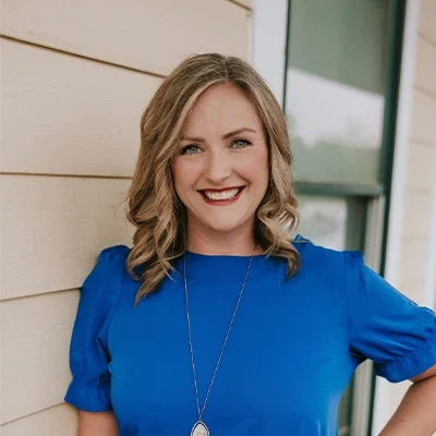 Chiropractor West St. Louis MO Ashley Brunjes Meet The Team Dr. Ashley Brunjes smiling in a blue shirt.